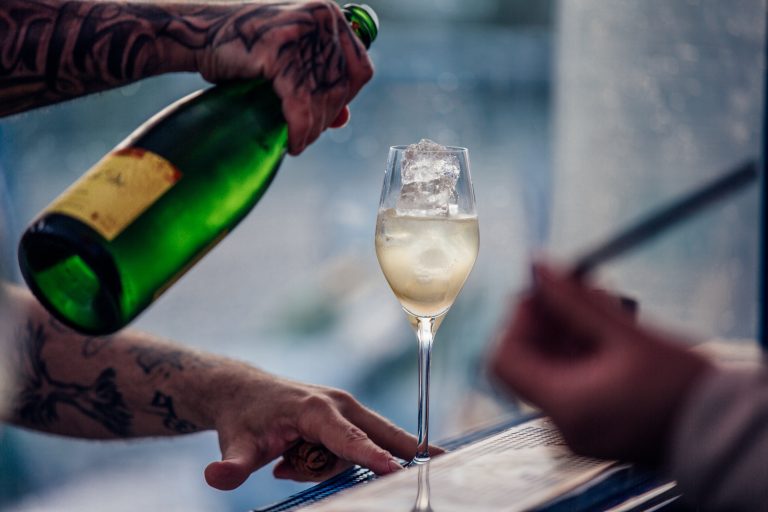 Barman versant du vin effervescent dans une flûte remplie de glaçons pour un spritz français