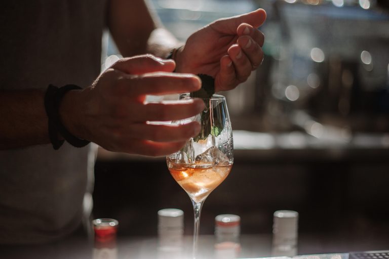 Barman ajoutant une feuille de menthe fraîche sur un spritz français à la Clairette de Die
